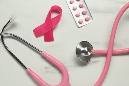 Pink ribbon, stethoscope and pills on white marble table, flat lay. Breast cancer awarenessの写真素材