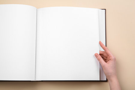 Woman with photo album at beige background, top view. Space for textの写真素材