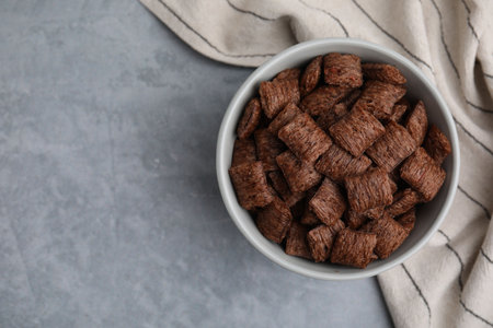 Chocolate cereal pads in bowl on gray table, top view. Space for textの写真素材
