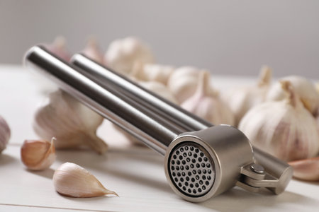 Metal press and garlic on white table, closeupの写真素材