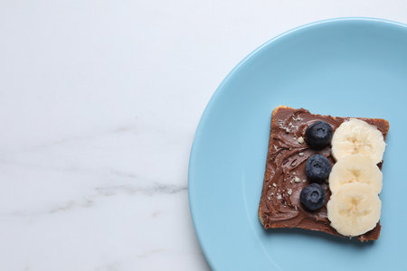 Toast with tasty nut butter, blueberries, banana and nuts isolated on white marble table, top view. Space for textの写真素材