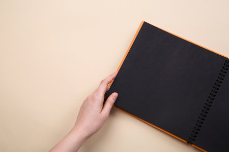 Woman with open photo album at beige background, top view. Space for textの写真素材