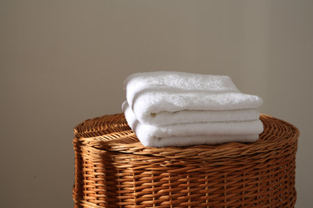 Soft towels on wicker basket indoors, space for textの写真素材