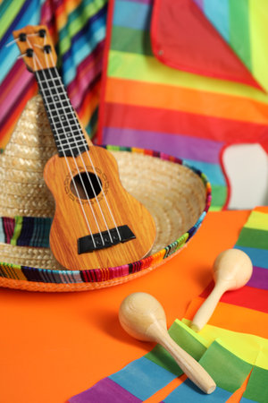 Mexican sombrero hat, ukulele and maracas on orange table, closeupの写真素材