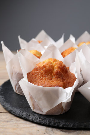 Delicious sweet muffins on wooden table against gray background, closeupの写真素材