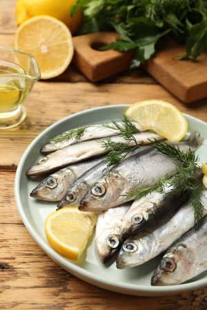 Fresh raw sprats, lemon and dill on wooden table, closeupの写真素材