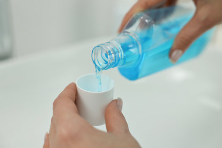 Young woman using mouthwash above sink in bathroom, closeupの写真素材