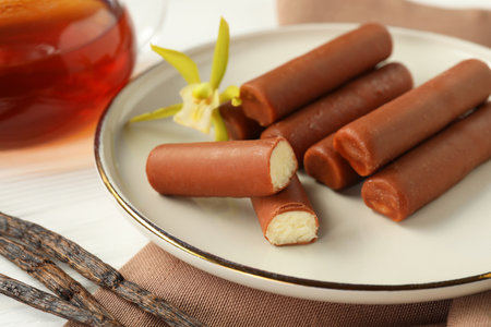 Glazed curd cheese bars, vanilla pods and flower on white wooden table, closeupの写真素材