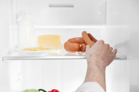Man taking sausages out of refrigerator, closeupの写真素材