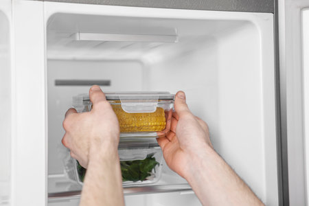 Man taking container with corn out of refrigerator, closeupの写真素材