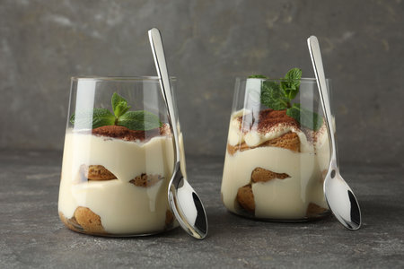Delicious tiramisu with mint in glasses on gray tableの写真素材