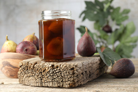 Jar of tasty sweet jam and fresh figs on wooden table