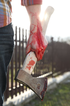 Man holding bloody ax outdoors, closeup viewの写真素材