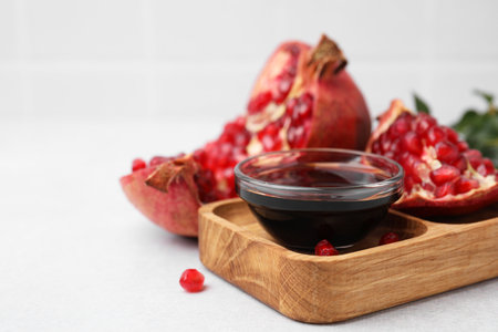 Tasty pomegranate sauce in bowl and fruits on light table, closeup. Space for textの写真素材