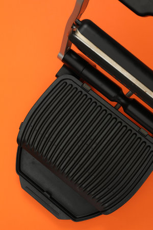 Electric grill on orange background, top view. Cooking appliance