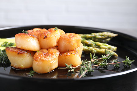 Delicious fried scallops with asparagus and thyme on plate, closeupの写真素材