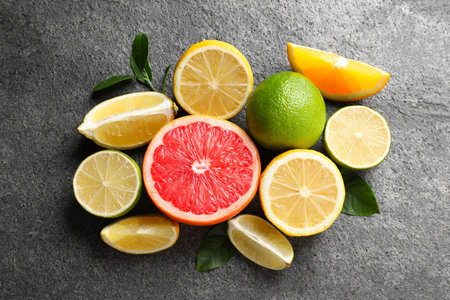 Different fresh citrus fruits and leaves on gray textured table, flat layの写真素材