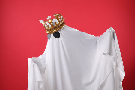 Person in ghost costume and luxurious crown on red backgroundの写真素材