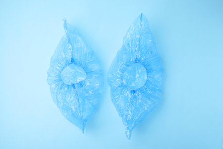Pair of medical shoe covers on light blue background, top view