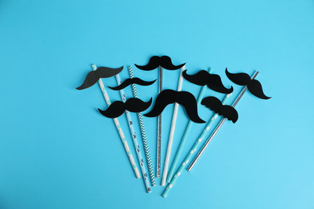 Fake paper mustaches with party props on light blue background, flat layの写真素材
