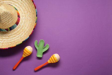 Mexican sombrero hat, maracas and toy cactus on violet background, flat lay. Space for textの写真素材