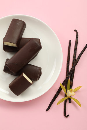 Glazed curd cheese bars, vanilla pods and flower on pink background, top viewの写真素材