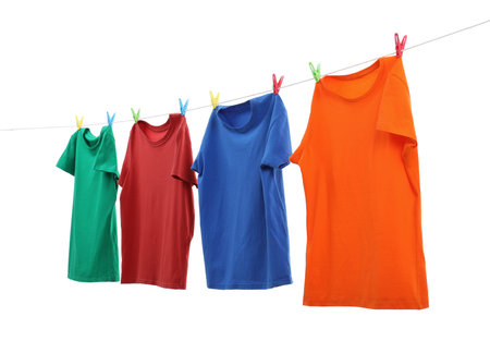 Colorful t-shirts drying on washing line isolated on whiteの写真素材