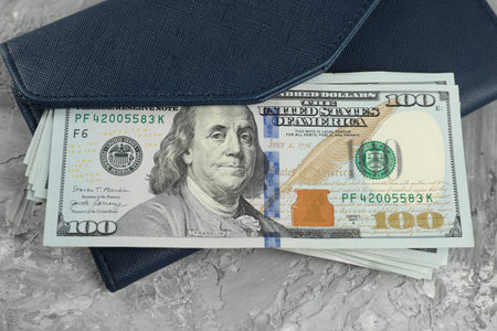 Money exchange. Wallet with dollar banknotes on gray stone background