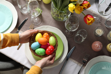 Woman setting table for festive Easter dinner at home, top view