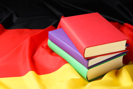 Learning foreign language. Different books on flag of Germany, space for textの写真素材