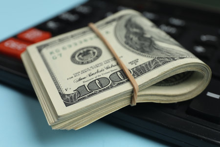 Money exchange. Dollar banknotes and calculator on light blue background, closeupの写真素材