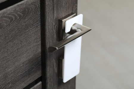 Wooden door with blank hanger on metal handle, closeupの写真素材