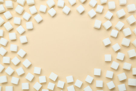 Frame made of white sugar cubes on beige background, top view. Space for text