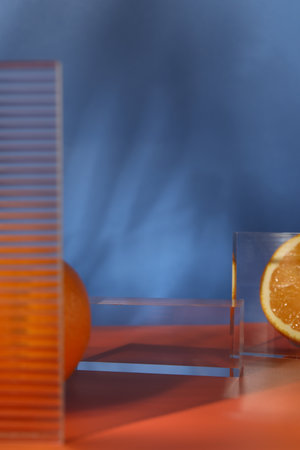 Presentation for product. Podium and tasty fresh oranges on red table against blue background, closeup. Space for textの写真素材