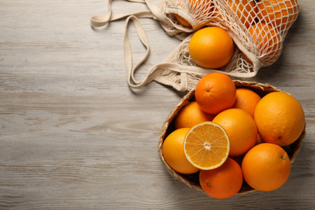whole Many and cut oranges on wooden table, flat lay. Space for text