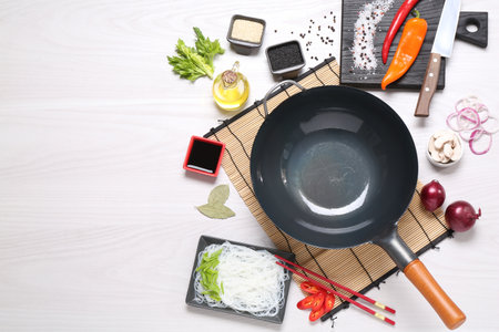 Wok, chopsticks and different products on white wooden table, flat lay. Space for textの写真素材