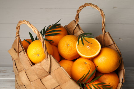 Wicker basket with whole and cut ripe oranges on wooden background, closeupの写真素材