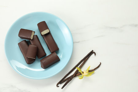 Glazed curd cheese bars, vanilla pods and flower on white marble table, flat lay. Space for textの写真素材