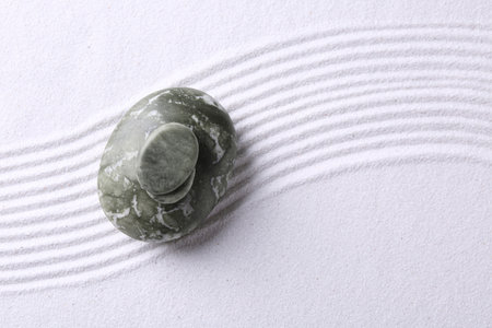 Zen garden stones on white sand with pattern, top view. Space for textの写真素材