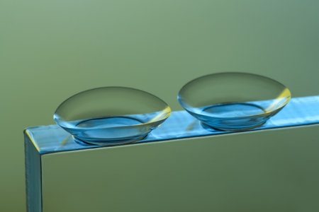 Pair of contact lenses on glass against gray background, closeupの写真素材