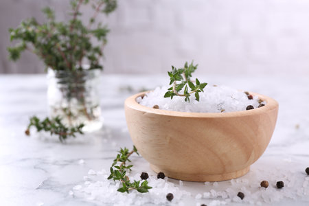 Salt with thyme and peppercorns in bowl on white marble table. Space for textの写真素材
