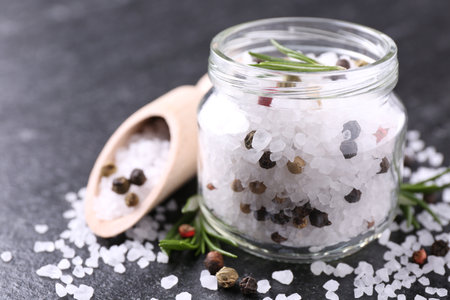 Salt with fresh rosemary and peppercorns on dark gray textured table, closeupの写真素材
