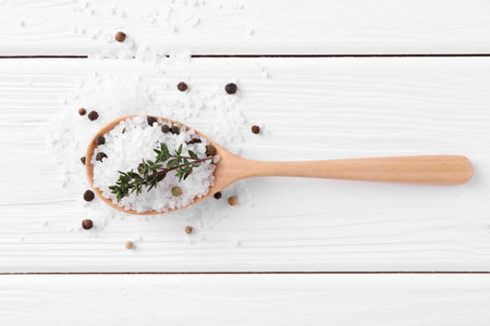 Salt with peppercorns, thyme and spoon on white wooden table, flat layの写真素材