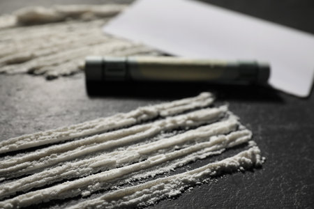 Drug addiction. Cocaine and rolled dollar banknote on dark textured table, closeupの写真素材
