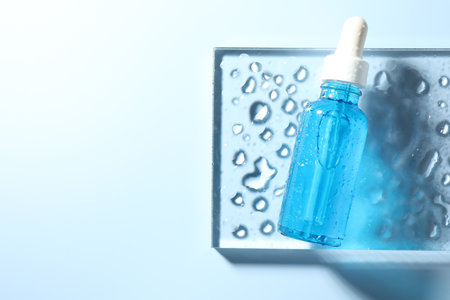 Bottle of cosmetic serum on light blue background, top view. Space for textの写真素材