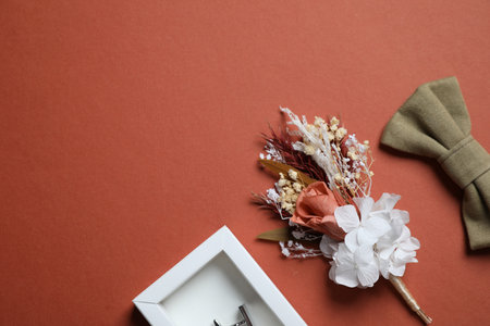 Wedding stuff. Stylish boutonniere, bow tie and cufflink on brown background, space for textの写真素材