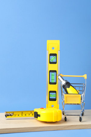 Small shopping cart with set of construction tools on light blue background