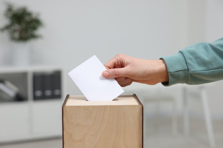 Woman putting her vote into ballot box on blurred background, closeupの写真素材