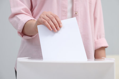 Woman putting her vote into ballot box on blurred background, closeupの写真素材