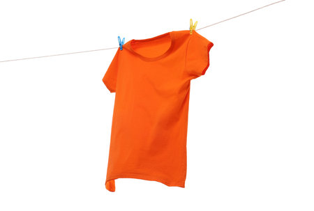 One orange t-shirt drying on washing line isolated on whiteの写真素材